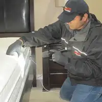 Bed bug inspection technician checking a mattress and bed frame for signs of infestation in Pasadena, CA