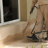 General pest control technician spraying exterior perimeter around a home in Pasadena, CA