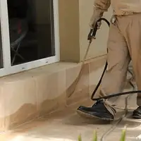 General pest control technician spraying exterior perimeter around a home in Pasadena, CA