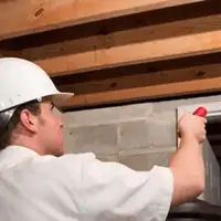 Termite inspection technician checking a basement wall and framing for termite activity in Pasadena, CA